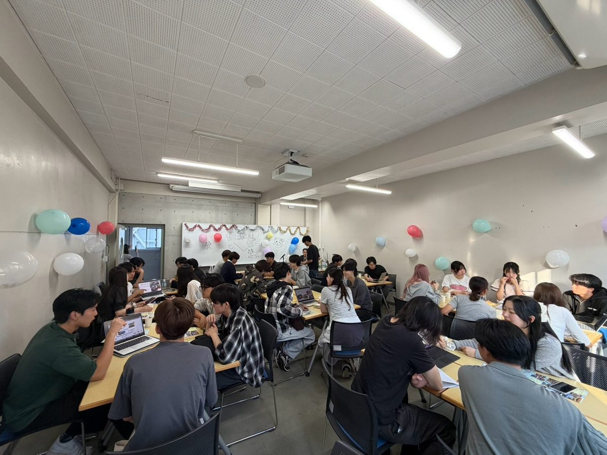装飾された相談会場で学生が研究会の話を聞く様子